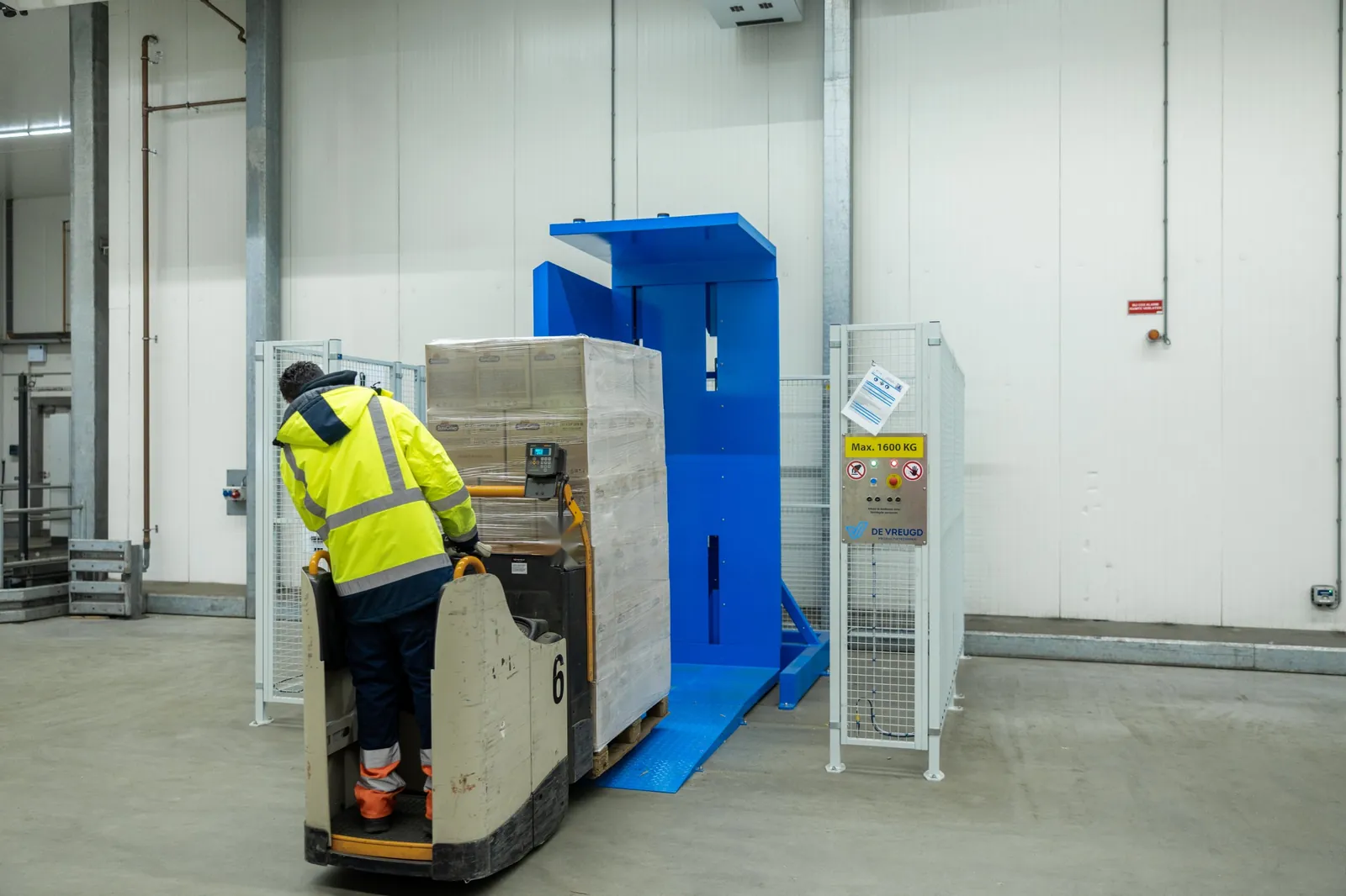 Un operatore sale con un transpallet elettrico e un pallet sulla rampa del ribaltatore di pallet PalletRotator EPT